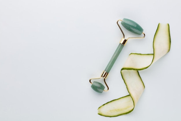 Ferramentas de massagem facial gua sha e pepino. rolo de jade de quartzo em fundo pastel. tratamento anti-idade, lifting e tonificação em casa.