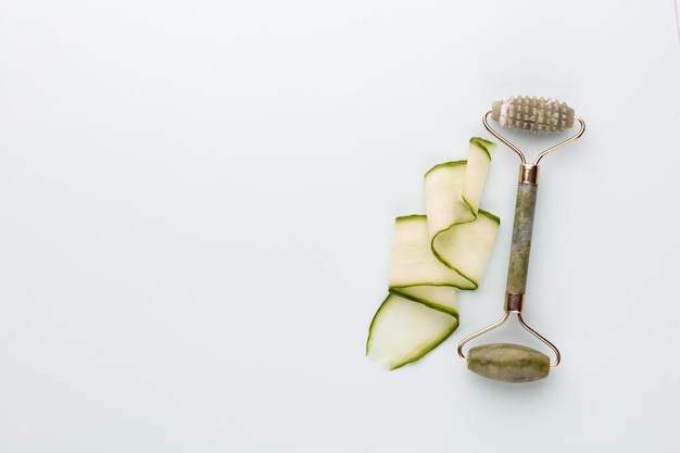 Ferramentas de massagem facial Gua Sha e rolo de jade de quartzo de pepino em fundo pastel Tratamento anti-idade e tonificação em casa