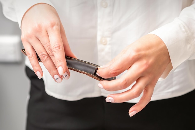 Ferramentas e mãos bem cuidadas para uma manicure. As mãos da manicure tiram o instrumento para uma manicure do estojo de couro em um salão de beleza.