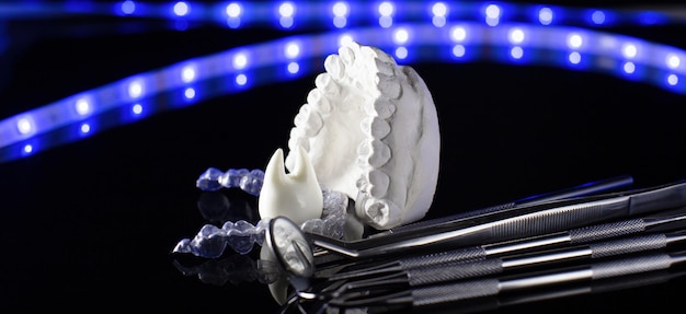 Ferramentas odontológicas e modelo de dentes em fundo neon Conceito de atendimento odontológico Aparelho invisível