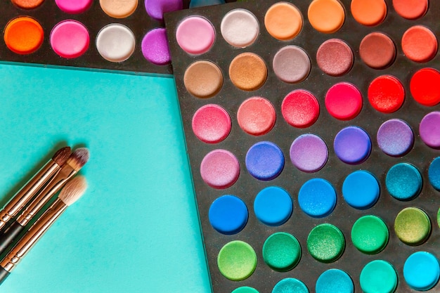 Foto ferramentas para maquiagem e cosméticos em diferentes tons de paleta de sombras e pincel de maquiagem em fundo colorido pastel azul moderno