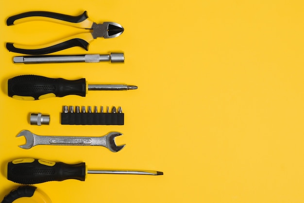 Foto ferramentas úteis amarelas e pretas (empilhadeiras e chave de fenda) isoladas em fundo amarelo