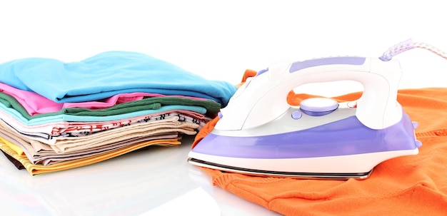 Ferro elétrico plano e roupas isoladas em branco