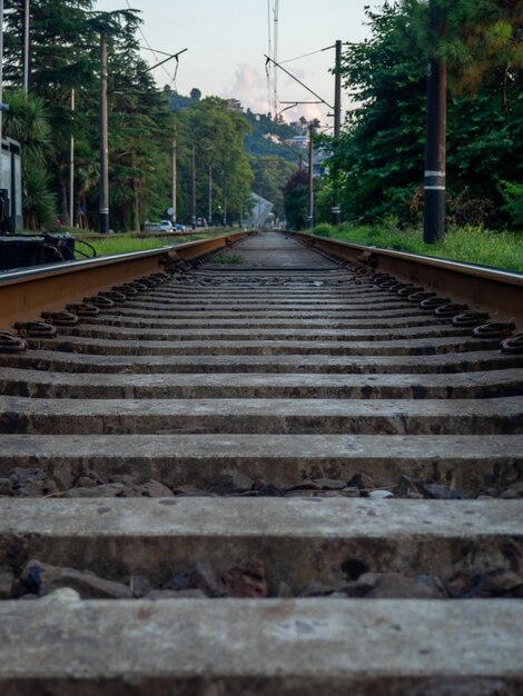 Ferrocarril en las afueras de la ciudad Camino para el transporte eléctrico entre los árboles Dormidores y rieles Concepto de cables de ruta y destino