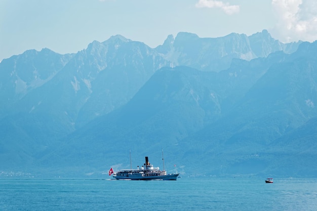 Ferry de agua con bandera suiza en el lago de Ginebra en el terraplén de Ouchy en Lausana, Suiza. personas a bordo