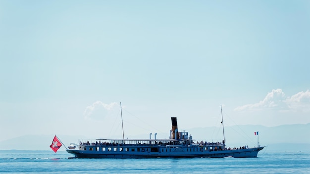 Ferry de agua con bandera suiza en el lago de Ginebra en el terraplén de Ouchy en Lausana, Suiza. personas a bordo