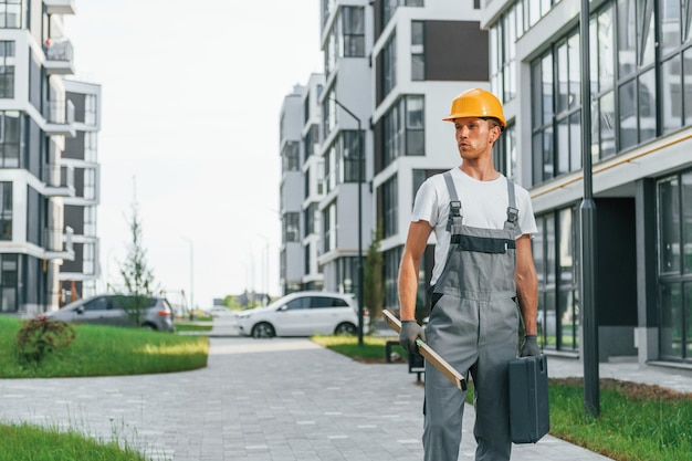 Fertige Gebäude Junger Mann, der tagsüber in Uniform am Bau arbeitet