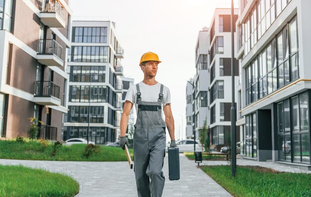 Fertige Gebäude Junger Mann, der tagsüber in Uniform am Bau arbeitet