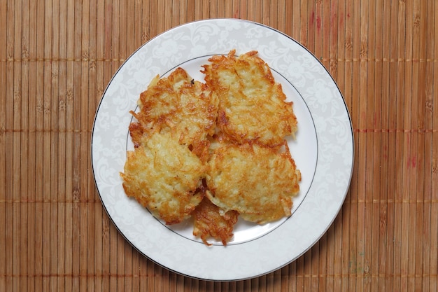 Fertige hausgemachte Kartoffelpuffer auf einem weißen Teller auf einem hölzernen Hintergrund Detailansicht von oben