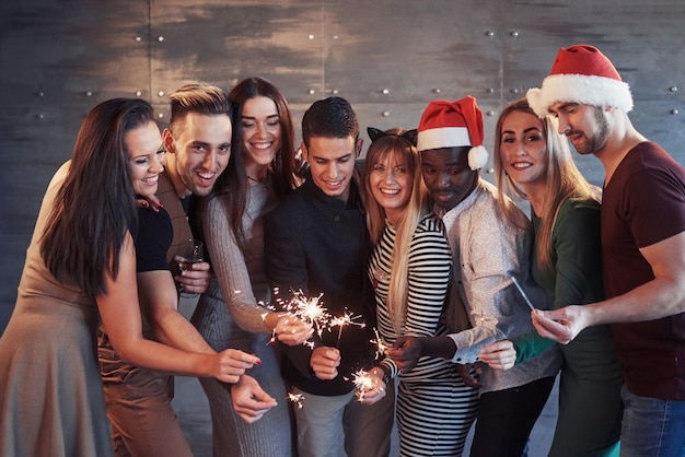 Festa com os amigos. grupo de jovens alegres carregando estrelinhas e taças de champagne