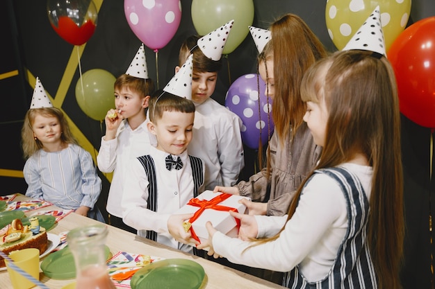 Festa de aniversário engraçada infantil no quarto decorado. crianças felizes com bolo e balões.