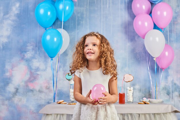 Festa de aniversário engraçado infantil no quarto decorado com balões. Menina feliz comemorar o dia internacional da criança. Brincadeira engraçada em casa