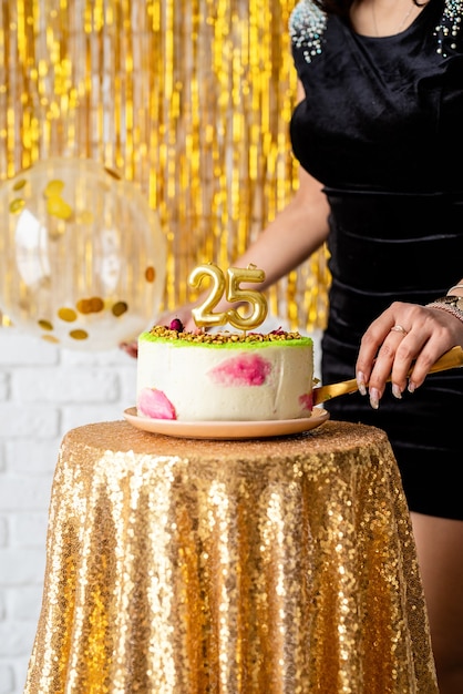 Foto festa de aniversário. linda mulher morena com vestido de festa preto segurando um balão para celebrar o aniversário dela cortando o bolo