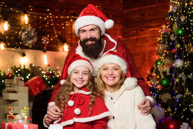 Foto festa de ano novo criança pequena e pais com chapéu de papai noel muitas caixas de presentes de natal feliz natal pai e mãe amam filha retrato família amorosa família feliz comemora o ano novo