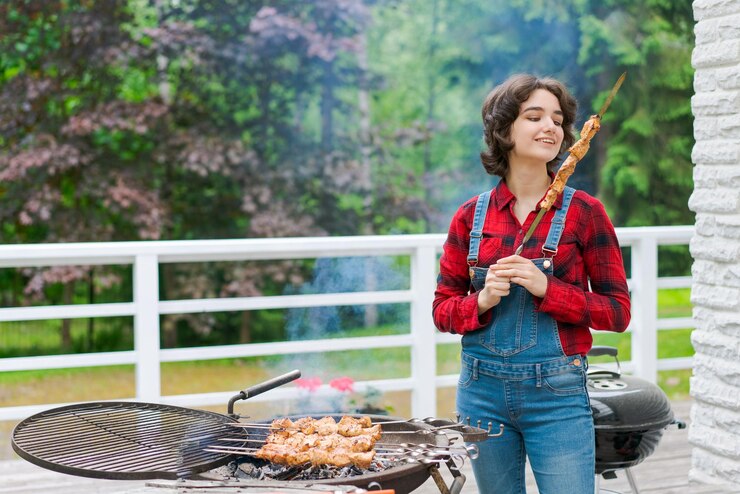 Foto festa de churrasco no jardim com jovem de macacão jeans e camisa xadrez vermelha