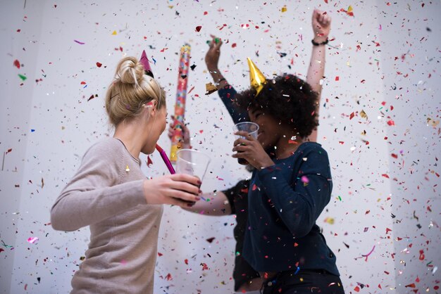 Foto festa de confete grupo de jovens felizes comemorando a véspera de ano novo enquanto dança e se diverte em casa