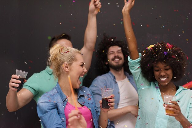 Foto festa de confete grupo multiétnico de jovens felizes comemorando a véspera de ano novo enquanto dança e se diverte em casa