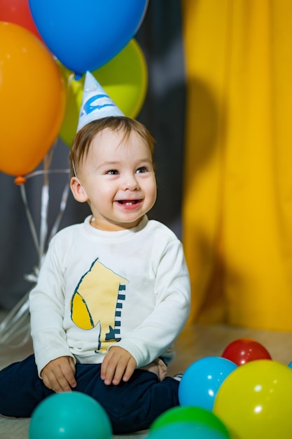 Foto festa do primeiro aniversário do menino menino feliz com balões coloridos