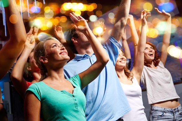 festa, feriados, celebração, vida noturna e conceito de pessoas - amigos sorridentes acenando as mãos no concerto no clube