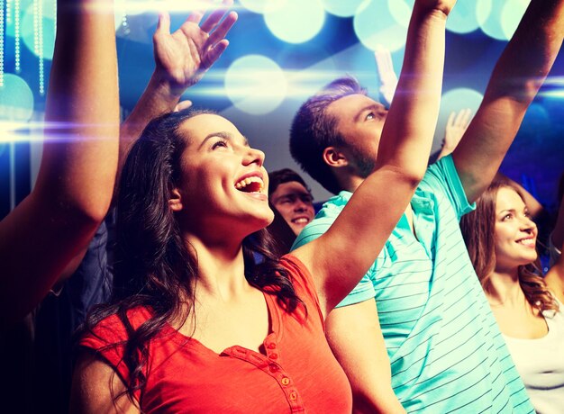 festa, feriados, celebração, vida noturna e conceito de pessoas - amigos sorridentes acenando as mãos no concerto no clube