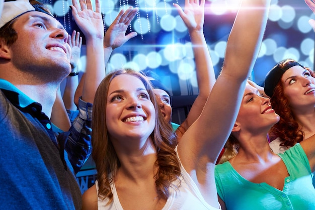 festa, feriados, celebração, vida noturna e conceito de pessoas - amigos sorridentes acenando as mãos no concerto no clube