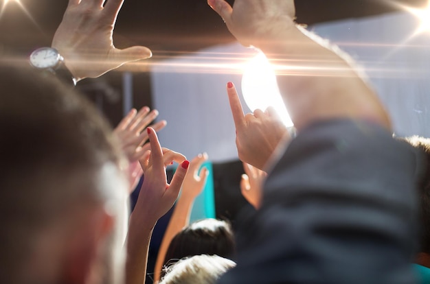 Foto festa, feriados, música, vida noturna e conceito de pessoas - close-up de pessoas felizes em concerto em boate acenando com as mãos