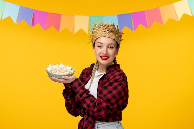 Festa junina blondes süßes mädchen im strohhut brasilianisches festival bunte flaggen mit schüsselpopcorn