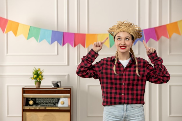 Foto festa junina linda chica con sombrero de paja verano brasileño con banderas coloridas de radio retro apuntando hacia arriba