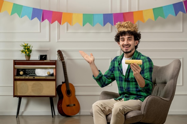 Festa junina lindo joven con sombrero de paja con radio retro y banderas coloridas con maíz