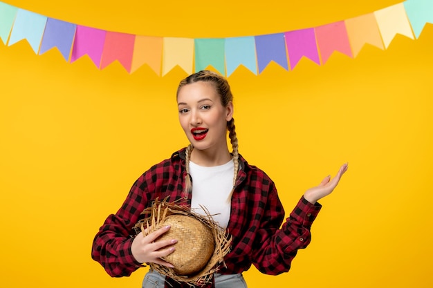 Foto festa junina loira linda garota segurando o festival brasileiro de chapéu de palha com bandeiras coloridas