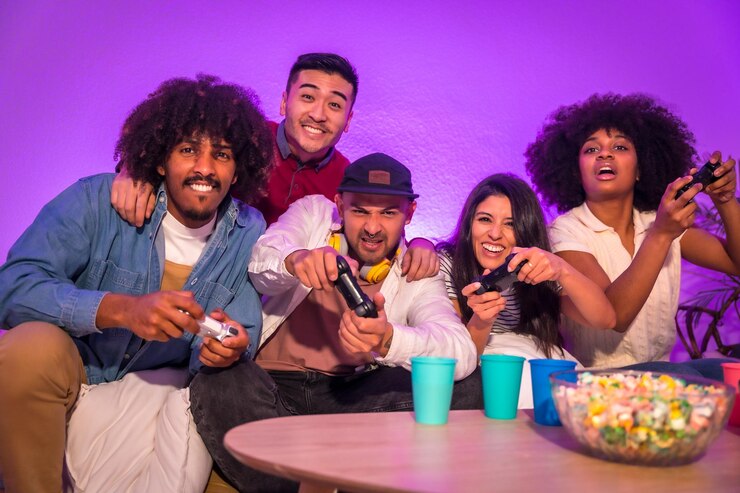 Foto festa para adultos jovens atraentes sentados no sofá jogando videogame com pipoca expressando alegria enquanto seguram o joystick e olham para o monitor