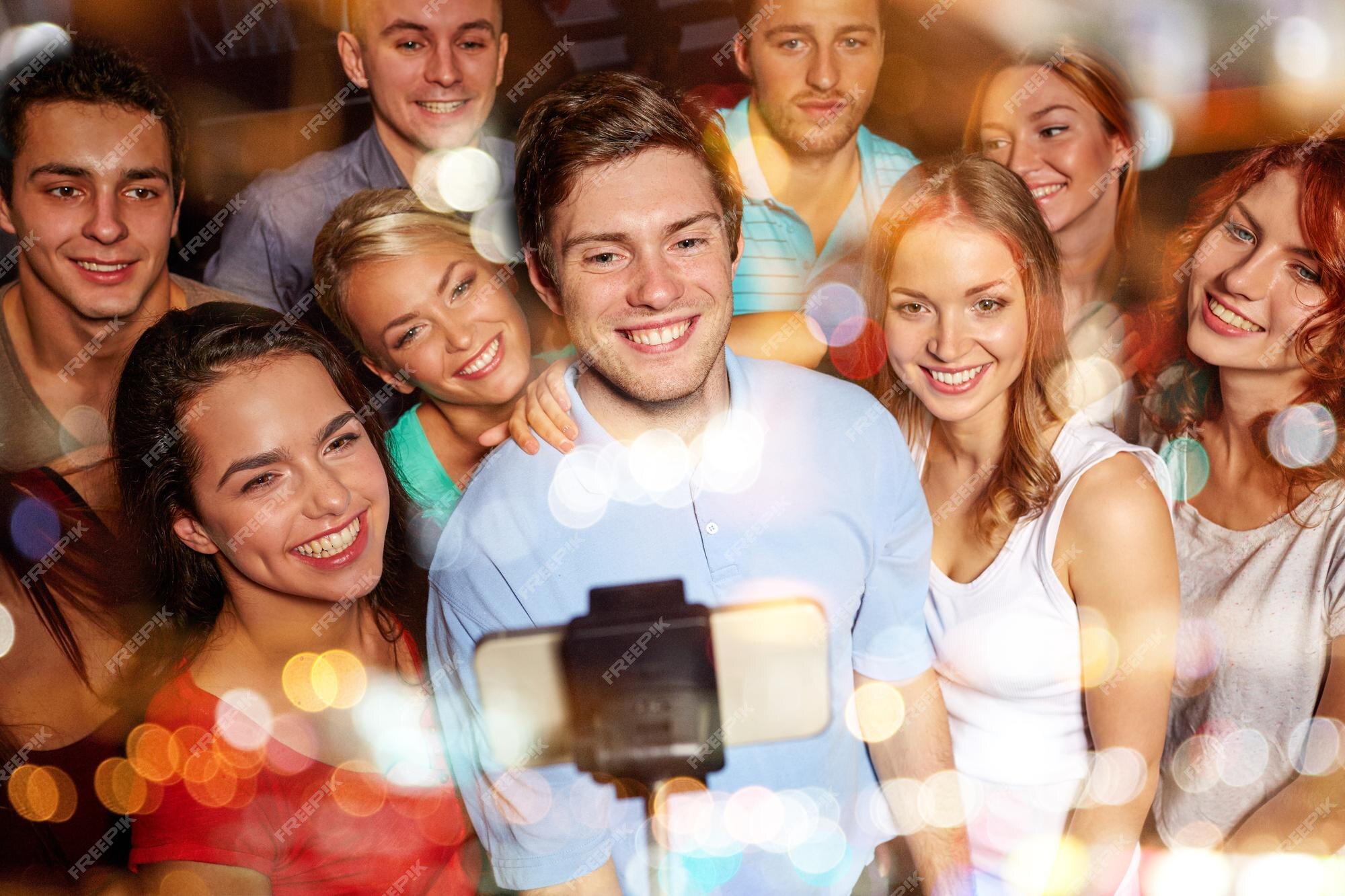 Festa, tecnologia, vida noturna e conceito de pessoas - amigos sorridentes  com smartphone tomando selfie no clube