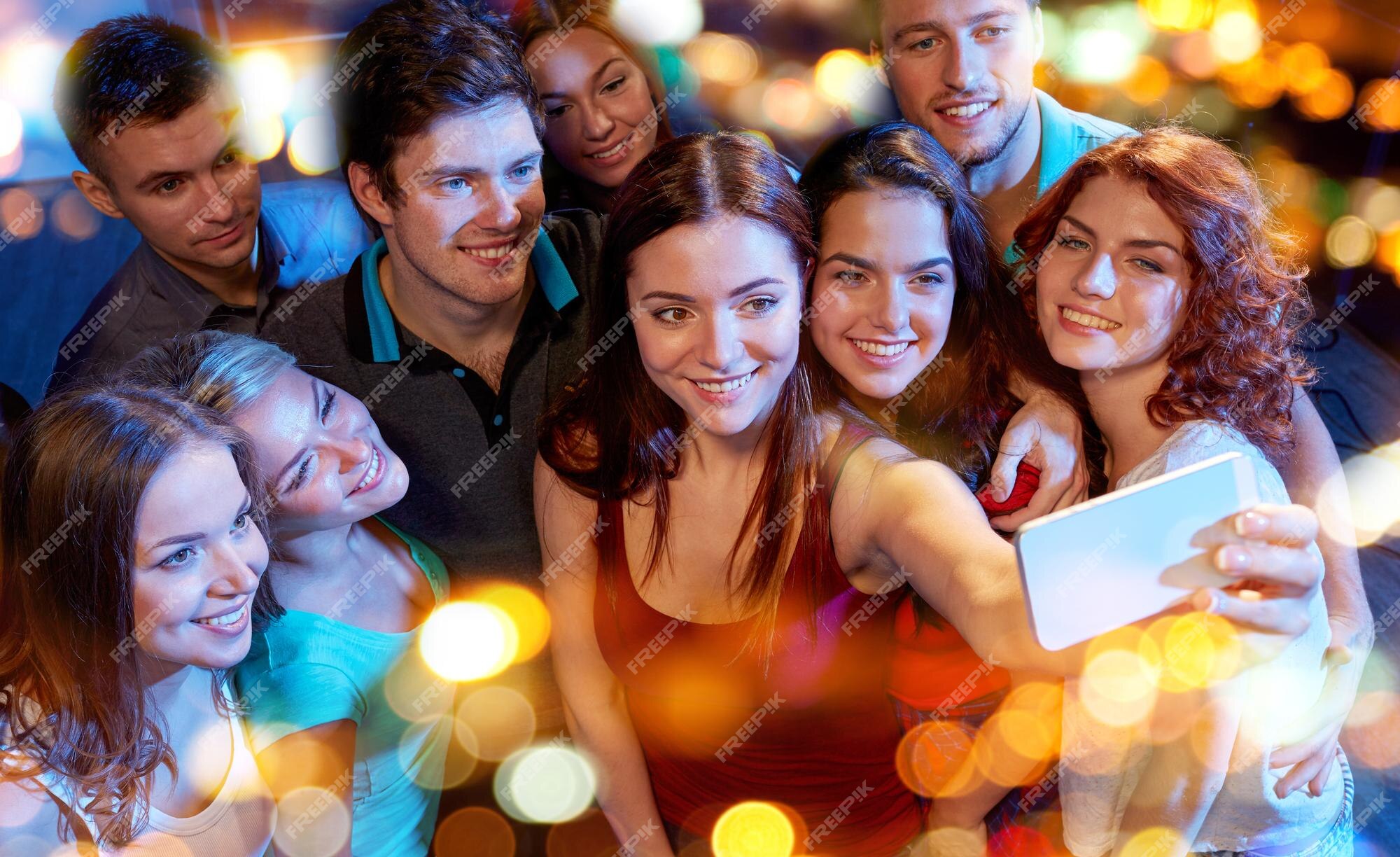 Festa, tecnologia, vida noturna e conceito de pessoas - amigos sorridentes  com smartphone tomando selfie no clube