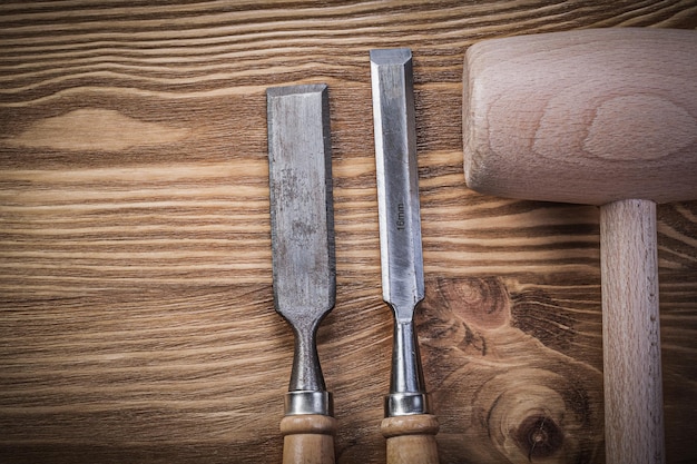 Festere Meißel aus Holzhammer auf Vintage-Holzbrett-Konstruktionskonzept.