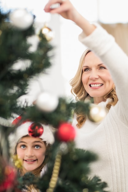 Festiva madre e hija decorar el árbol de Navidad