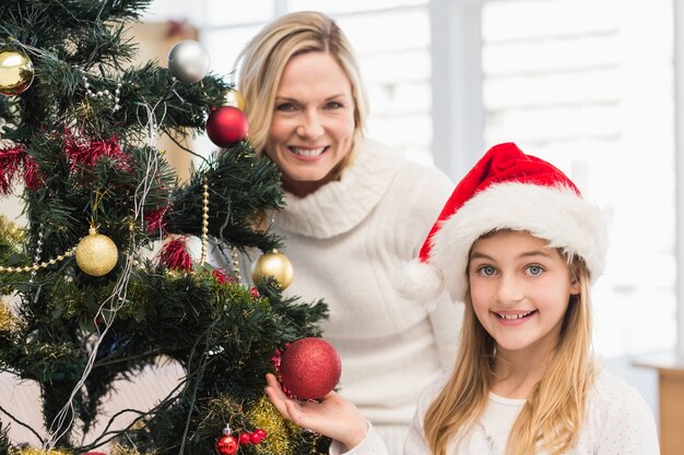 Festiva madre e hija decorar el árbol de Navidad