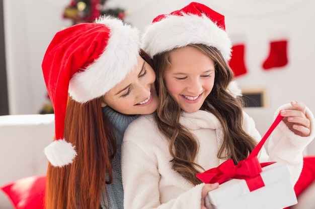 Festiva mãe e filha no sofá com presente