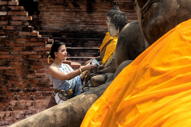 Festival de Thaland. Mulher de Ásia que veste a Buda de reclinação do traje tailandês do tradional que banha-se no festival da água do dia de Songkran em Tailândia.