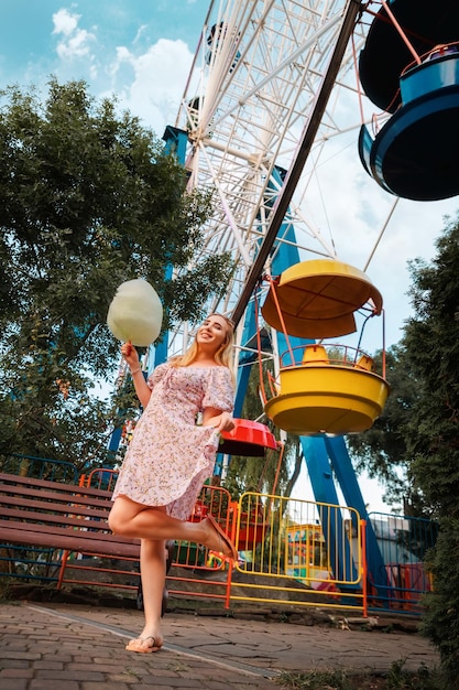 Festival de verão mulher bonita sonhadora comendo um algodão doce no parque de diversões vertical o conceito de férias férias e felicidade