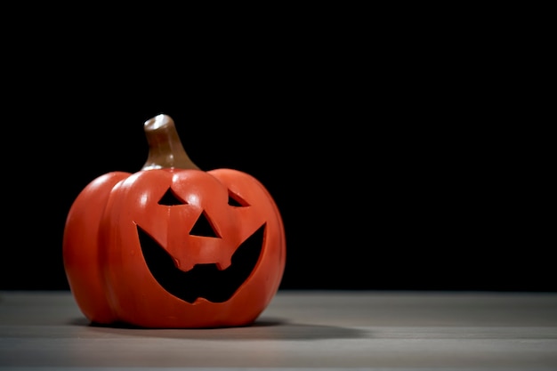 Festival de Halloween calabaza Jack O lantern en mesa de madera frente a espeluznante fondo oscuro con textura para diseño de banner