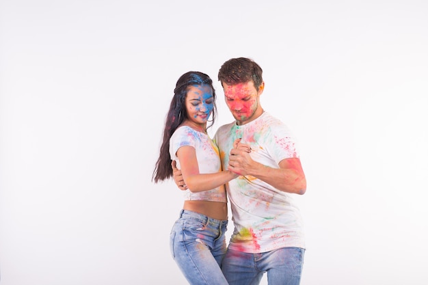 Festival de holi, danza social, amistad: jóvenes jugando con colores en el festival de holi y bailando bachata o kizomba en una superficie blanca con espacio de copia