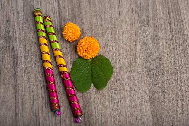 Festival indiano dussehra e navratri, mostrando folha dourada (bauhinia racemosa) e flores de calêndula com varas dandiya em uma mesa de madeira