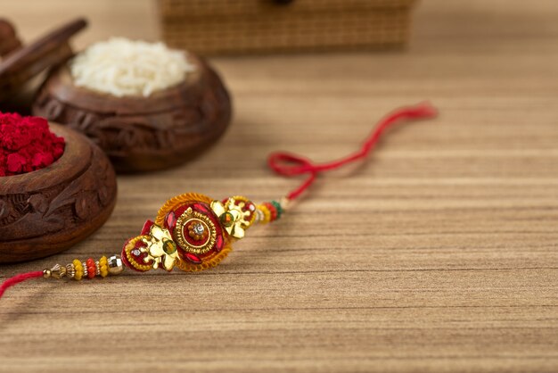 Festival indiano: fundo Raksha Bandhan com um elegante Rakhi, grãos de arroz e Kumkum