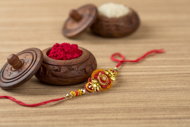 Festival indiano: fundo Raksha Bandhan com um elegante Rakhi, grãos de arroz e Kumkum