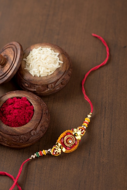 Festival indiano: fundo Raksha Bandhan com um elegante Rakhi, grãos de arroz e Kumkum