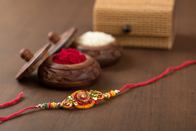 Festival indiano: fundo raksha bandhan com um elegante rakhi, grãos de arroz e kumkum