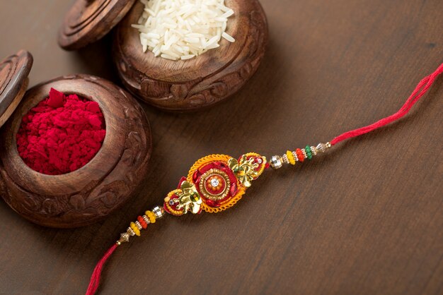 Festival indiano: fundo Raksha Bandhan com um elegante Rakhi, grãos de arroz e Kumkum