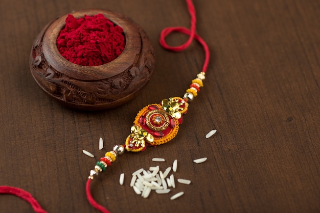 Festival indiano: fundo Raksha Bandhan com um elegante Rakhi, grãos de arroz e Kumkum