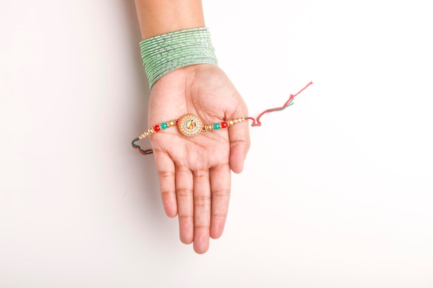 Foto festival indiano raksha bandhan mão feminina segurando pulseira em fundo branco