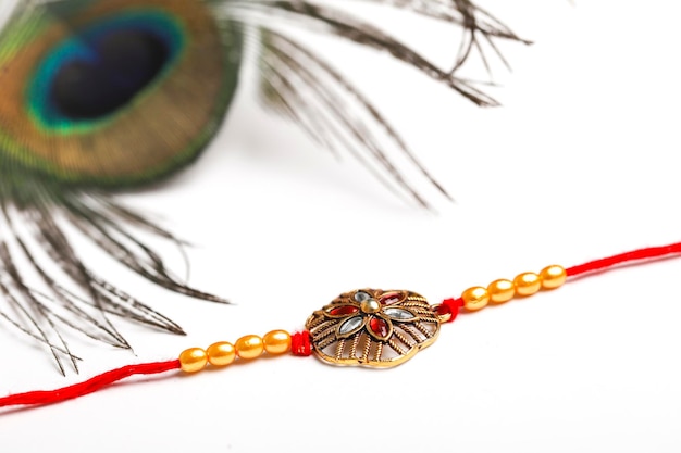 Festival indiano raksha bandhan Rakhi ou pulseira com pena de pavão em fundo branco